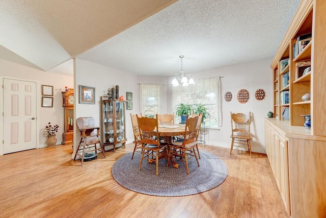 dining room featuring light hardwood / wood-style flooring, a textured ceiling, and a notable chandelier