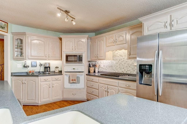 kitchen featuring light hardwood / wood-style floors, stainless steel appliances, backsplash, and cream cabinets