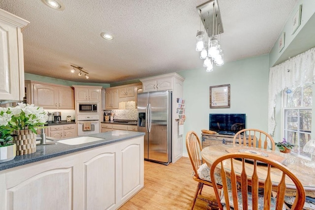 kitchen with light hardwood / wood-style flooring, oven, built in microwave, stainless steel fridge, and kitchen peninsula