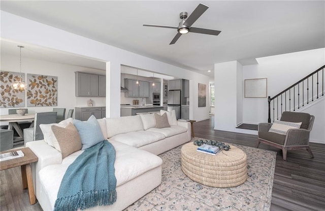 living room with ceiling fan with notable chandelier, dark hardwood / wood-style floors, and sink