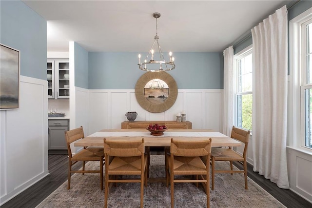 dining room with dark wood-type flooring, plenty of natural light, and a notable chandelier