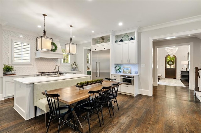 kitchen featuring stainless steel appliances, crown molding, backsplash, light countertops, and a sink