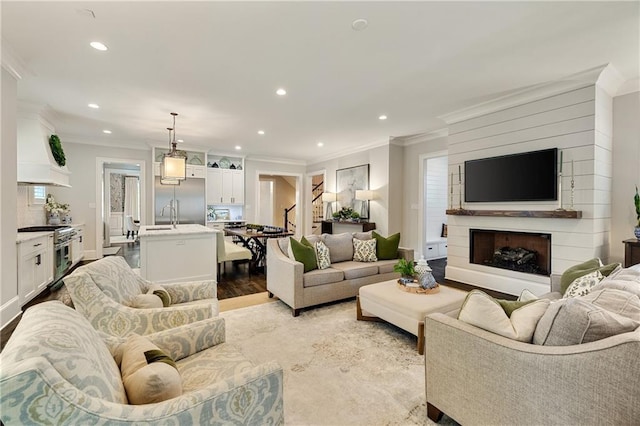 living area featuring crown molding, recessed lighting, a fireplace, baseboards, and wood finished floors