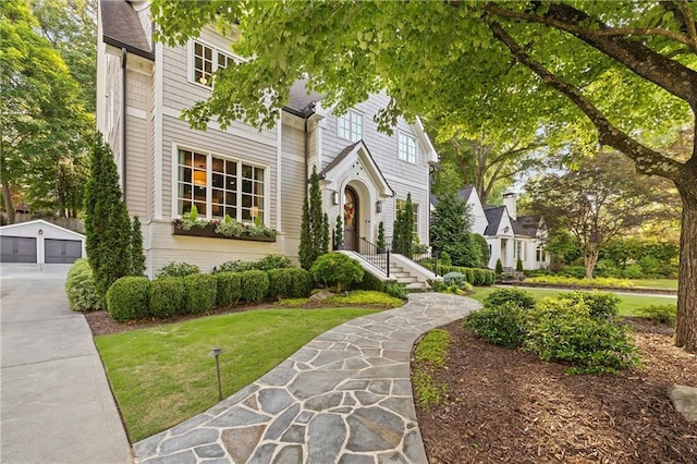 view of front of property featuring an outbuilding, a detached garage, and a front lawn