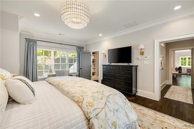 bedroom with wood finished floors, baseboards, ornamental molding, a chandelier, and a spacious closet
