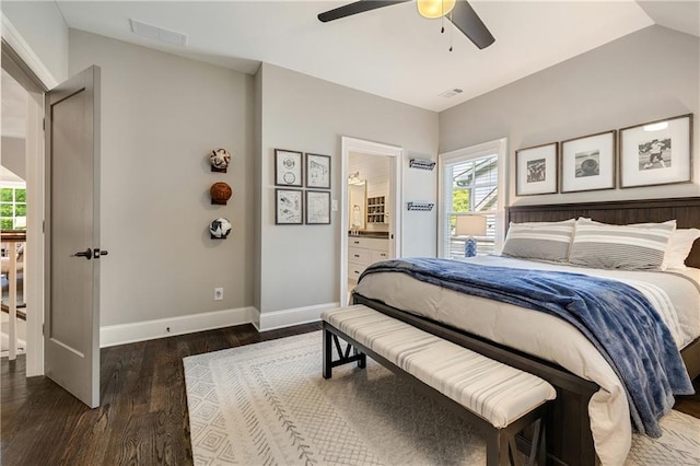 bedroom featuring wood finished floors, baseboards, multiple windows, lofted ceiling, and ensuite bath