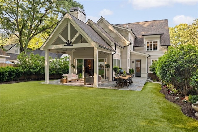rear view of house featuring outdoor lounge area, a patio area, a ceiling fan, a chimney, and roof with shingles