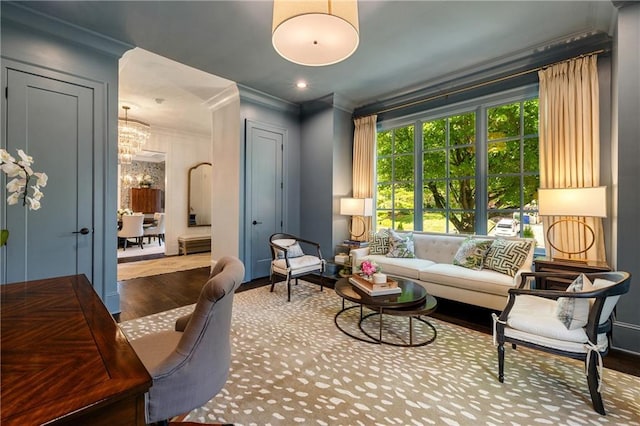 living area featuring ornamental molding, wood finished floors, a chandelier, and baseboards
