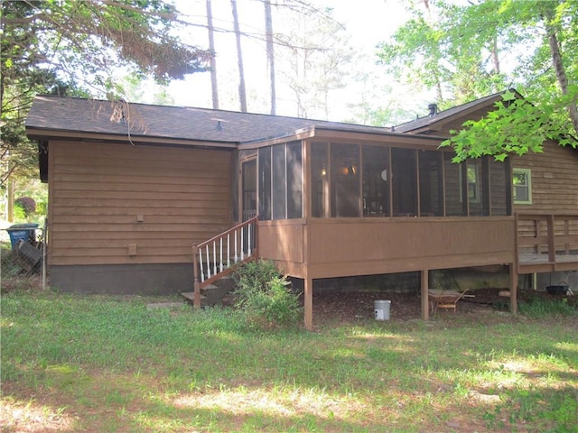 rear view of house featuring a sunroom, roof with shingles, and a lawn
