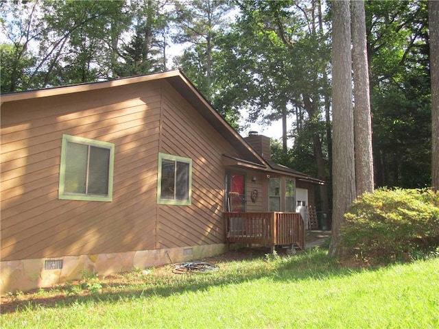 view of home's exterior featuring crawl space, a lawn, a chimney, and an attached garage