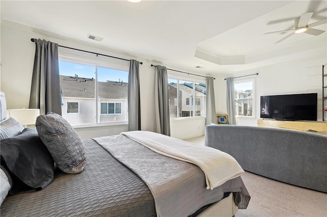 bedroom featuring ceiling fan, light colored carpet, ornamental molding, and a tray ceiling