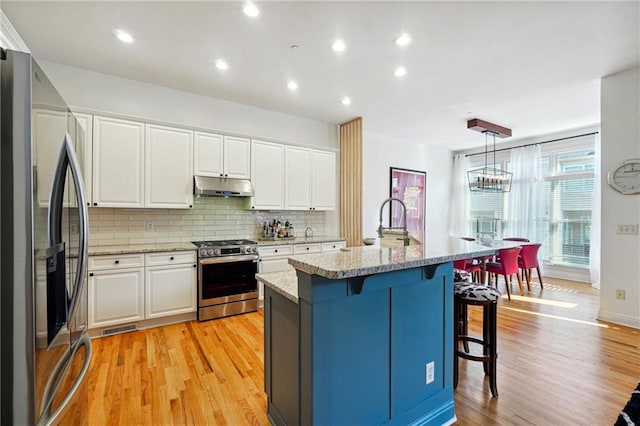 kitchen with a center island with sink, light hardwood / wood-style floors, white cabinetry, and stainless steel appliances