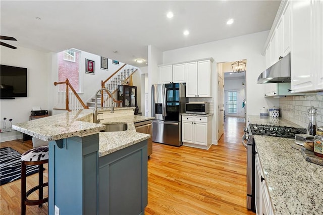 kitchen with white cabinets, sink, stainless steel appliances, and an island with sink