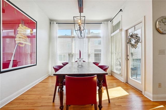 dining space with wood-type flooring, an inviting chandelier, and a wealth of natural light