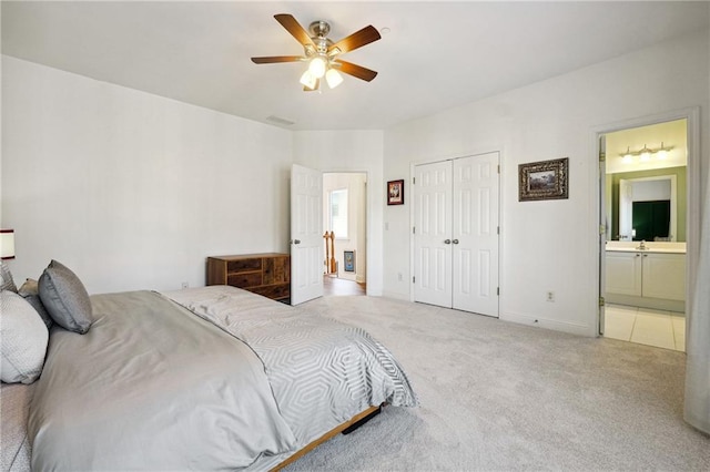 carpeted bedroom with ensuite bathroom, a closet, and ceiling fan