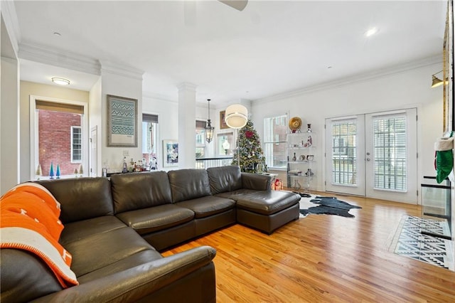 living room with french doors, ornamental molding, and light wood-type flooring