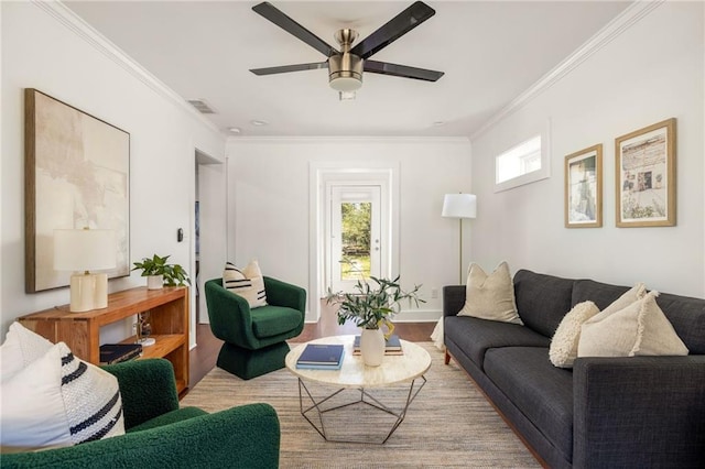 living room with ceiling fan, wood finished floors, visible vents, and ornamental molding