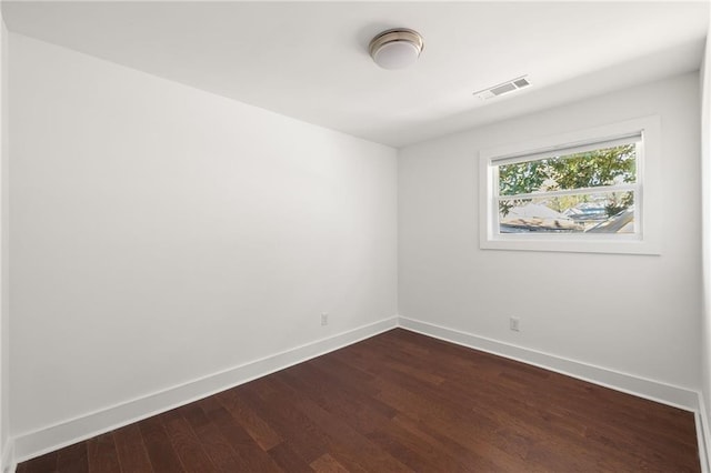 unfurnished room with visible vents, baseboards, and dark wood finished floors