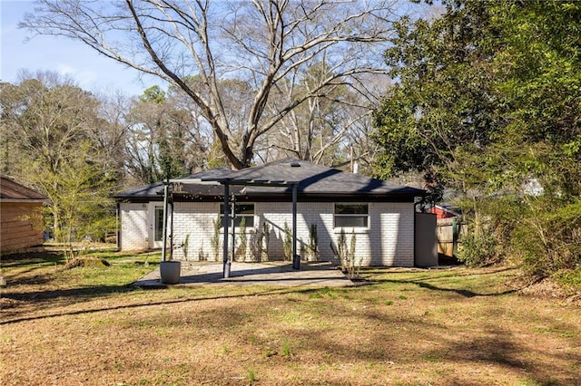 back of house featuring brick siding, a patio area, and a lawn