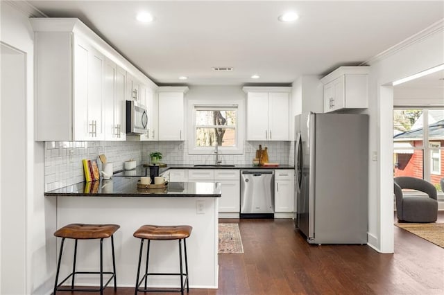 kitchen with white cabinetry, a peninsula, dark wood-style flooring, and stainless steel appliances