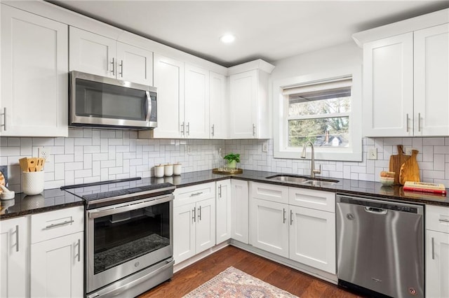 kitchen with backsplash, dark wood finished floors, appliances with stainless steel finishes, white cabinetry, and a sink