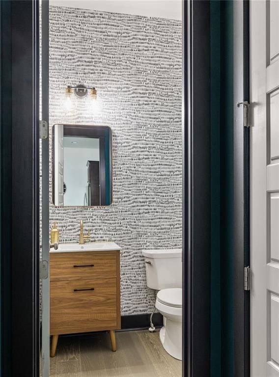 bathroom with toilet, wood-type flooring, and vanity