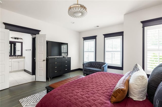 bedroom with ensuite bath and light wood-type flooring