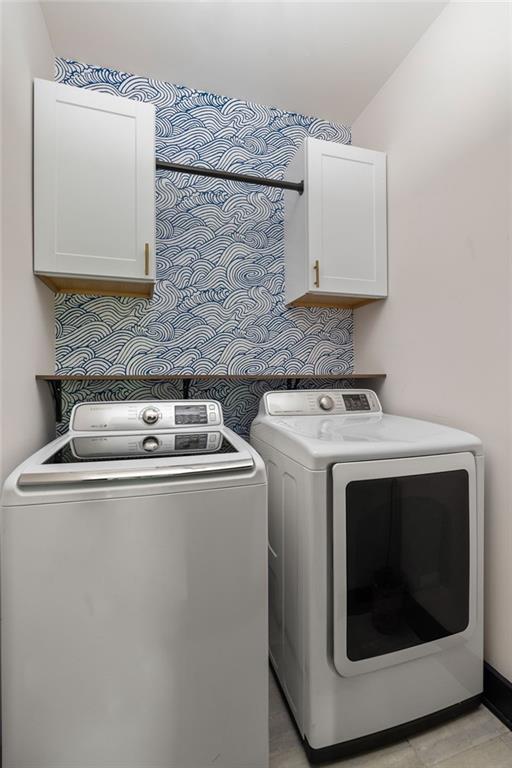 clothes washing area with cabinets and independent washer and dryer