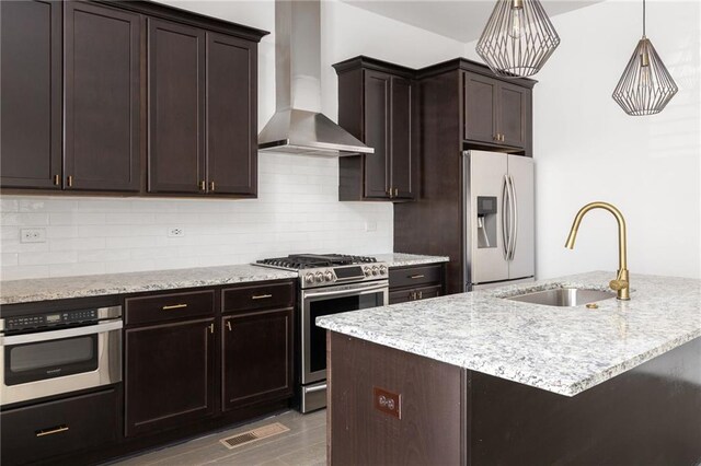 kitchen with wall chimney exhaust hood, stainless steel range with gas cooktop, tasteful backsplash, and sink