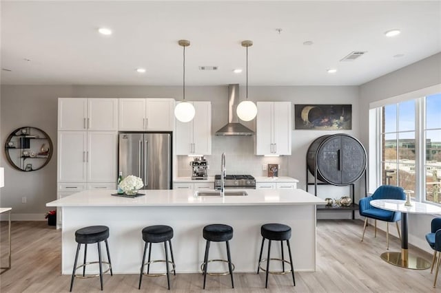 22 Airline St NE Unit 403, Atlanta, GA 30312 - kitchen featuring stainless steel fridge, wall chimney range hood, a sink, a kitchen island with sink, and white cabinetry
