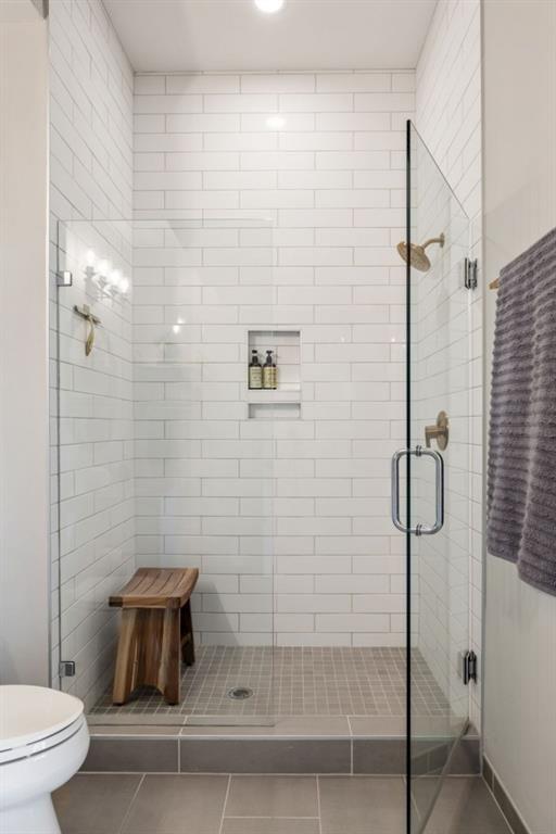 bathroom featuring tile patterned floors, toilet, and a stall shower