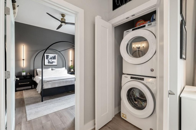 laundry area featuring wood-type flooring, stacked washer and clothes dryer, and ceiling fan