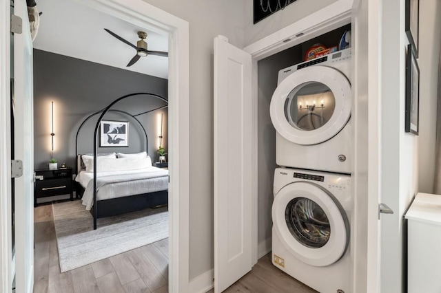 laundry area featuring a ceiling fan, laundry area, wood finished floors, and stacked washer and clothes dryer