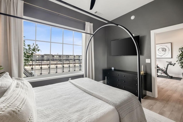 bedroom with a ceiling fan, wood finished floors, visible vents, and baseboards