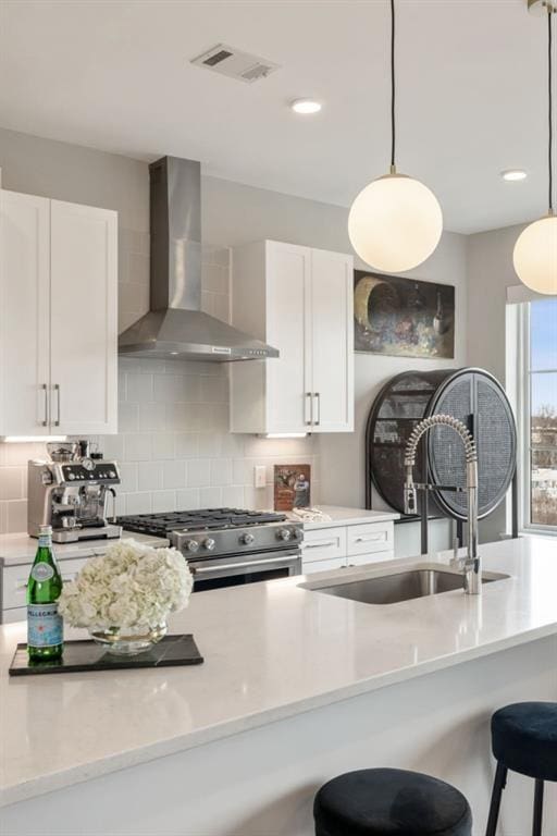 kitchen featuring tasteful backsplash, stainless steel range, wall chimney exhaust hood, and a sink