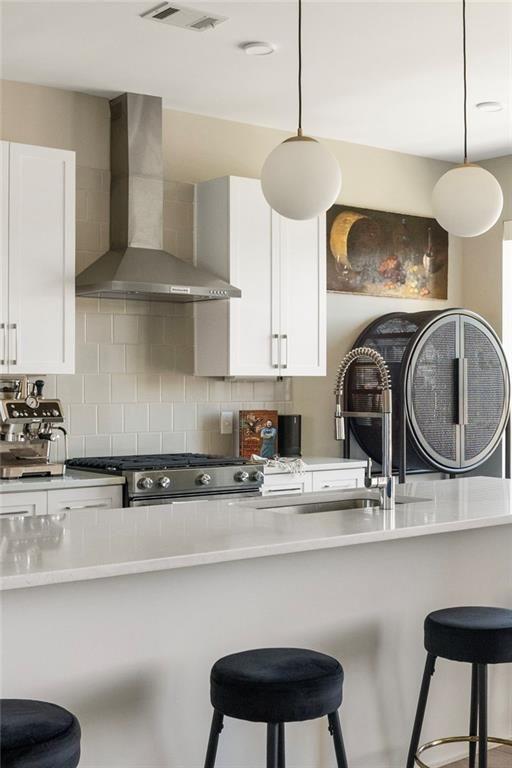 22 Airline St NE Unit 403, Atlanta, GA 30312 - kitchen featuring wall chimney exhaust hood, range, a sink, white cabinets, and backsplash