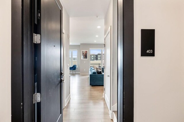 hall featuring recessed lighting, baseboards, and light wood finished floors