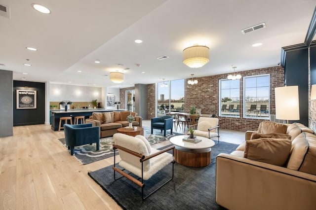 living room featuring visible vents, recessed lighting, brick wall, and light wood-style floors