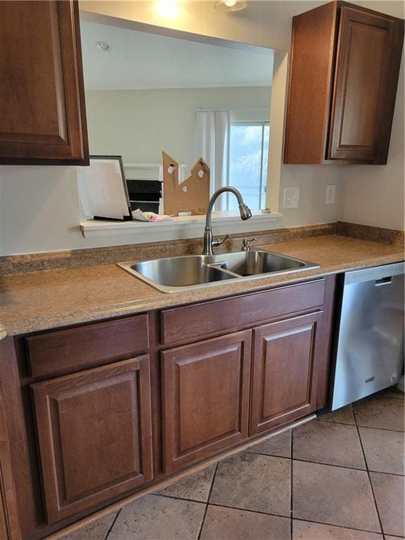 kitchen featuring stainless steel dishwasher, light tile patterned floors, and a sink