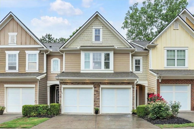 view of property with an attached garage, board and batten siding, driveway, and roof with shingles