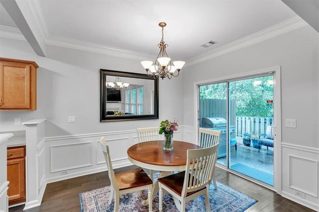 dining room with an inviting chandelier, visible vents, ornamental molding, and dark wood-style floors