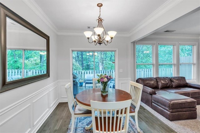 dining room featuring an inviting chandelier, crown molding, plenty of natural light, and wood finished floors