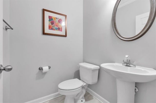bathroom with a sink, toilet, and baseboards