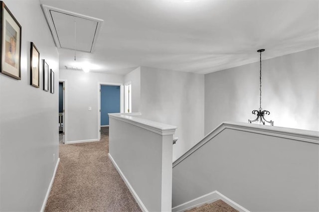 corridor featuring attic access, an upstairs landing, baseboards, and carpet