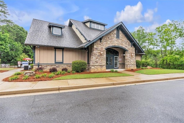craftsman-style home with stone siding, french doors, a shingled roof, and board and batten siding