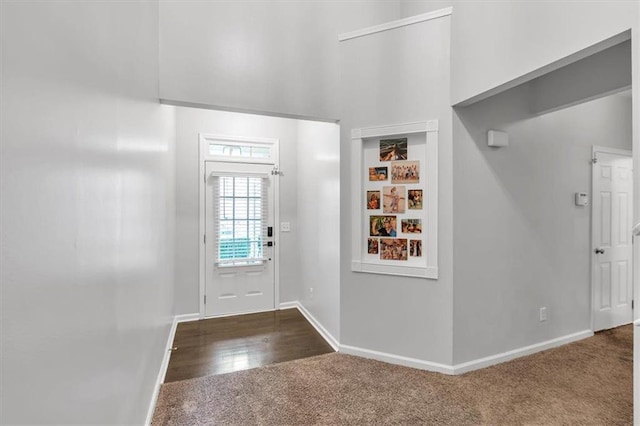 carpeted entrance foyer with baseboards and a high ceiling
