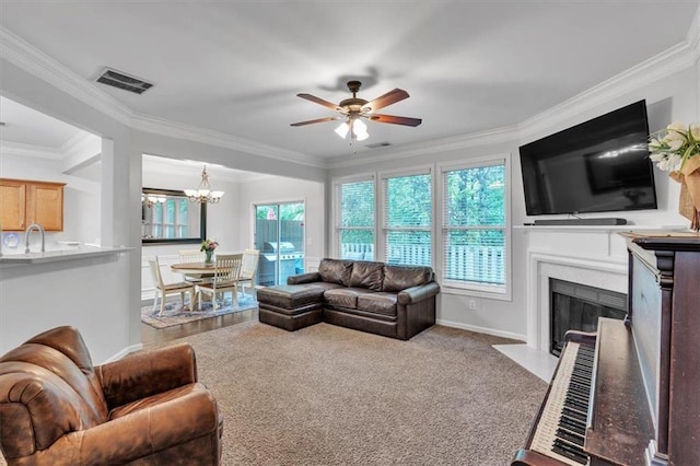 living area featuring ceiling fan with notable chandelier, a fireplace with flush hearth, visible vents, baseboards, and ornamental molding