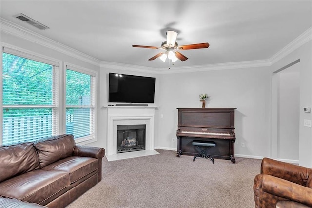 living room featuring carpet flooring, a fireplace, crown molding, visible vents, and ceiling fan