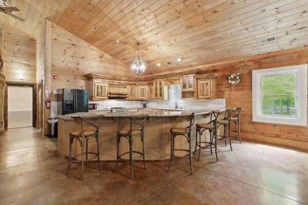 230 Old Mill White Ext, Jasper, GA 30143 - kitchen with wood ceiling, black refrigerator with ice dispenser, wooden walls, a peninsula, and concrete flooring