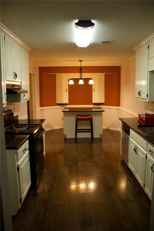 kitchen with hanging light fixtures, black electric range oven, stainless steel dishwasher, and dark hardwood / wood-style floors